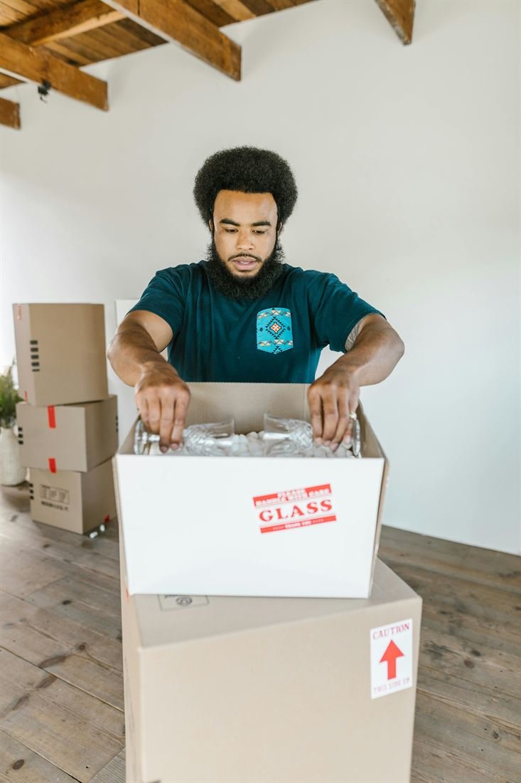 Express mover packing fragile glassware into a labelled box with bubble wrap